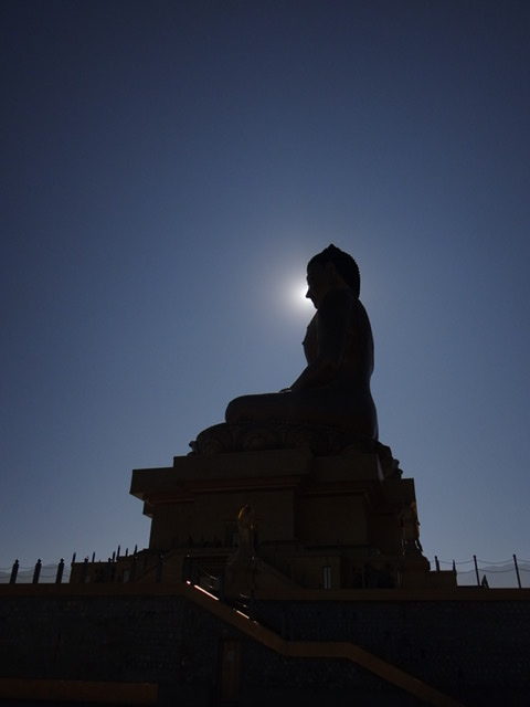 The shadow of the largest sitting Buddha in the world against the sun in Bhutan
