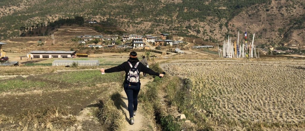 My sister walking in between dry rice fields in Bhutan