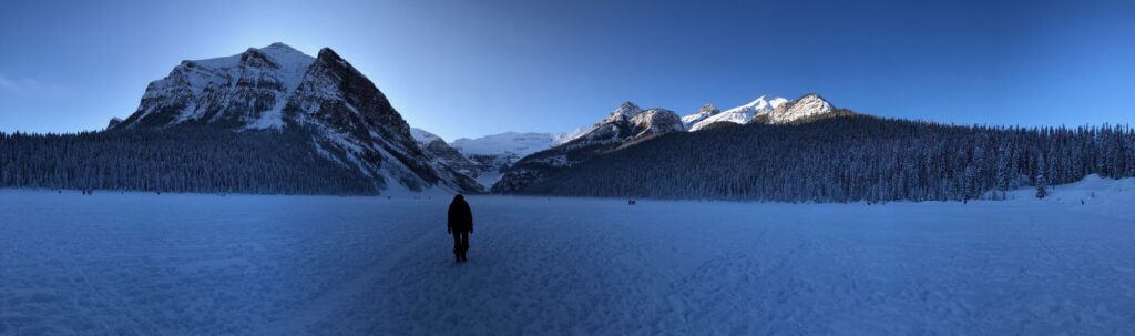 Me walking in the frozen Lake Louise in Banff with two mountains in the back