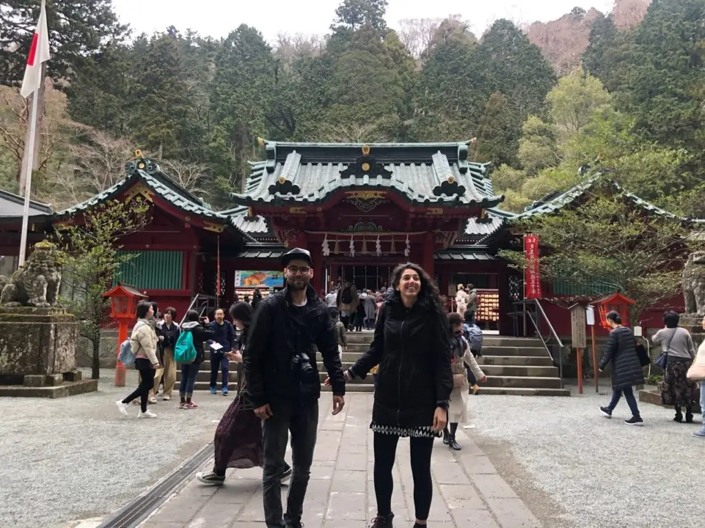 Couple holding hands and posing in front of temple in Japan