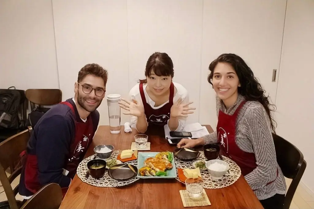 Couple with their finished meal prepared with their teacher who is in the middle