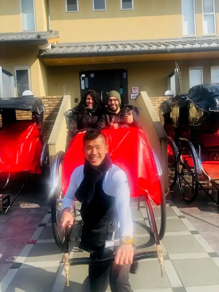 Man and woman in a rickshaw ride with their smiling driver 