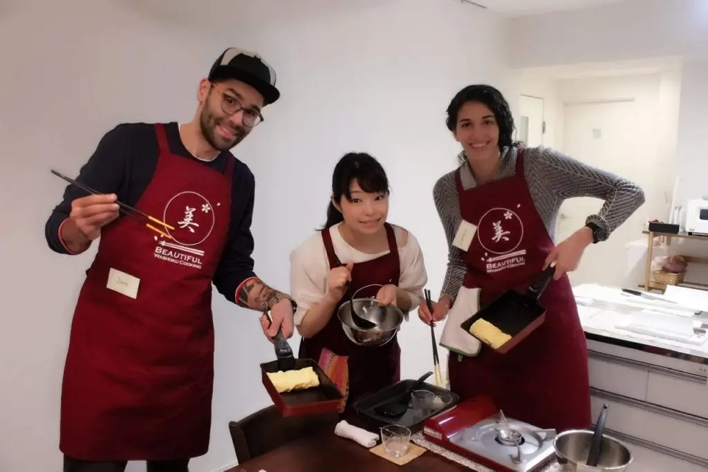 Man and woman in a cooking class with Japanese woman in the middle on their honeymoon in Japan