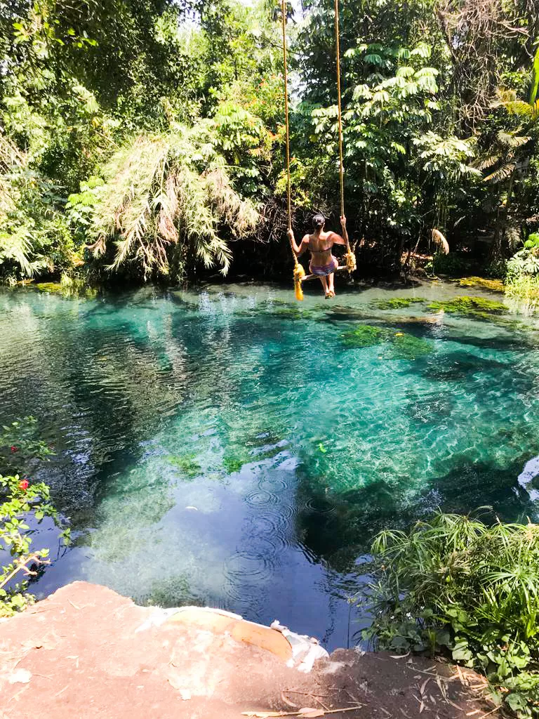 Woman on swing on top of crystaline waters on the river in Las Estacas close to Mexico City