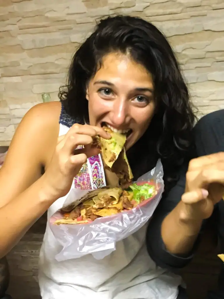 Woman eating tacos de canasta in Mexico city