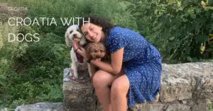 a photo of a woman in a blue dress with hugging two dogs, one white and one brown, with the text Croatia with dogs
