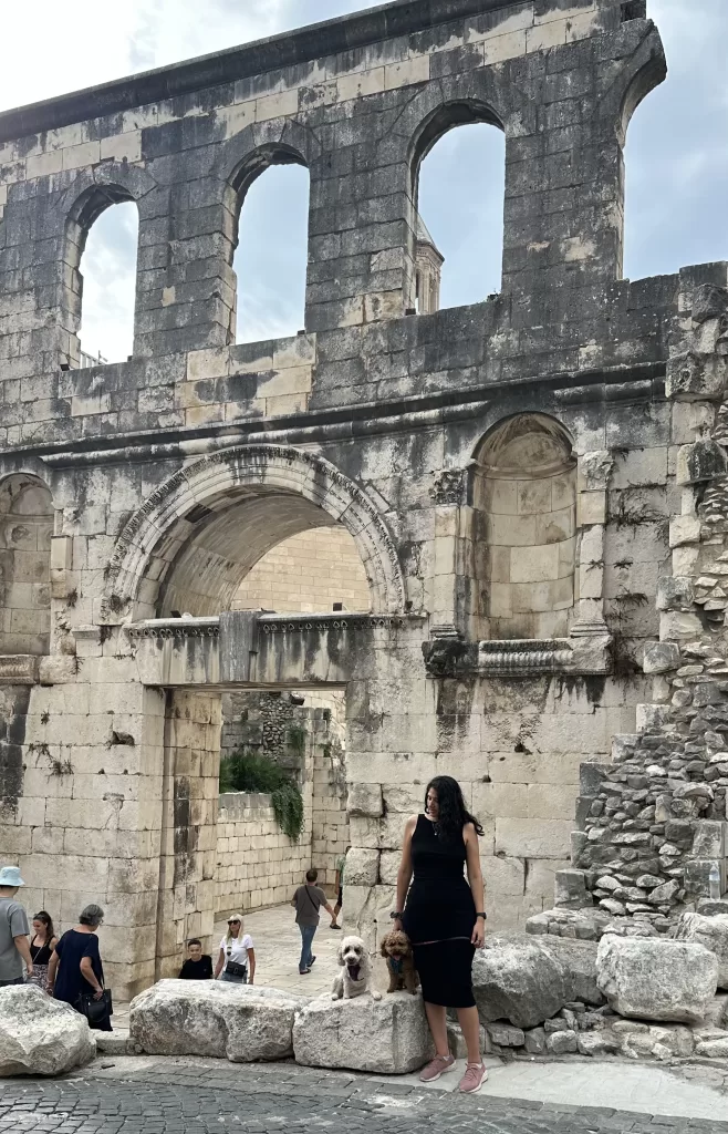 Woman in black dress and two dogs in front of Eastern gate to Diocletian’s palace is one of the best dog friendly activities in croatia