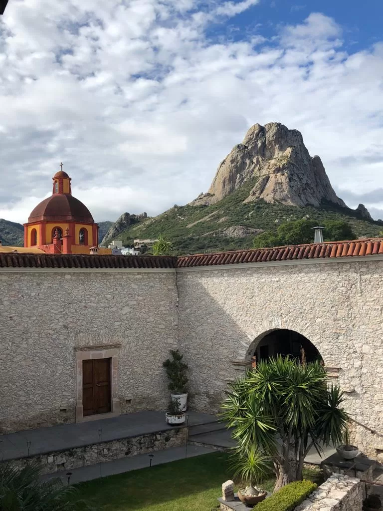 Stone wall, church cupula, and pena de bernal monolith