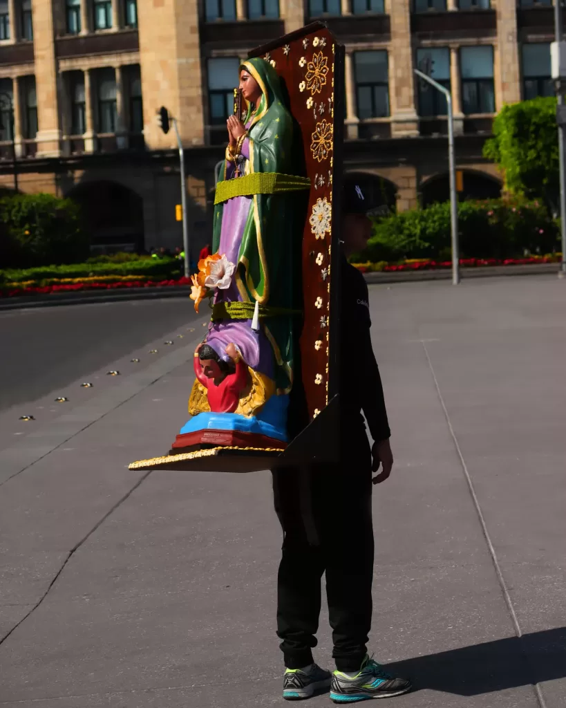 Man with a virgin of guadalupe statue strapped to his back