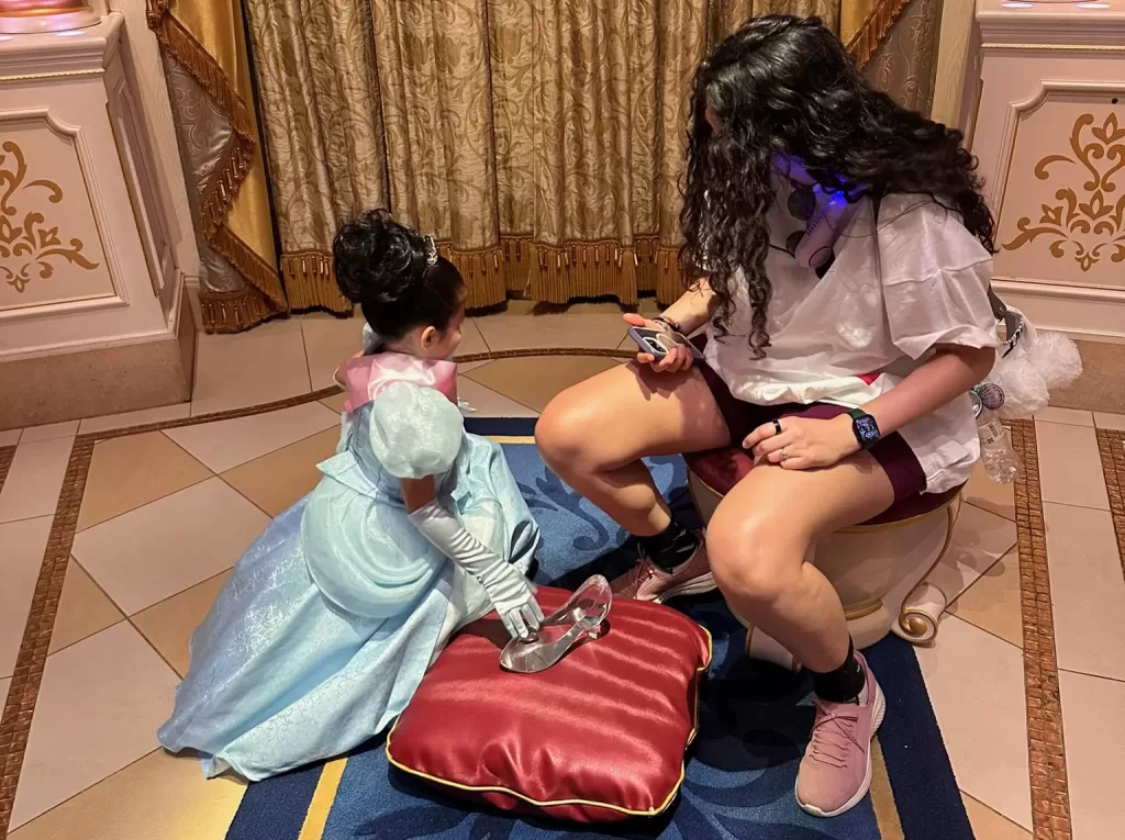 Me trying on the Cinderella’s glass slipper inside Cinderlla’s Castle in Tokyo Disneyland with a little girl dressed as Cinderella in kneeling in front of me